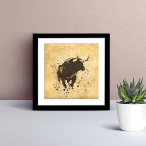 May include: A black and white illustration of a bull charging on a textured, yellow background with splattered paint.