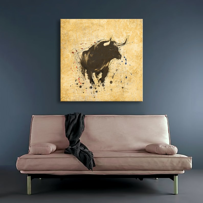 May include: A black bull silhouette with horns against a yellow background with splattered paint. The bull is facing left and is in a charging pose. The background is a textured yellow with red, blue, and white paint splatters.