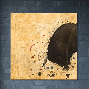 May include: A black bull silhouette with a white horn is painted on a textured, yellow background with red and blue paint splatters.