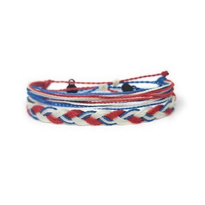 May include: A stack of braided and string bracelets in red, white, and blue. The bracelets are in a patriotic color scheme, with a braided bracelet at the bottom and several string bracelets on top. The bracelets are on a white background.