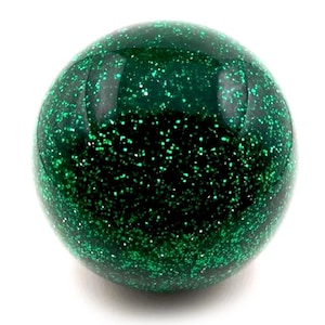 May include: A spherical decorative object, dark green in colour, with a speckled, glittery finish. The surface reflects light, creating a sparkling effect. The sphere is set against a plain white background, highlighting its colour and texture.