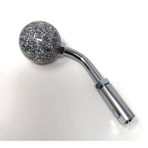 以下が含まれることがあります： 銀色とキラキラで覆われたボール型のギアシフトノブ。湾曲したクロムメッキの金属アームが付いています。ギアシフトノブはメタリックな仕上がりです。