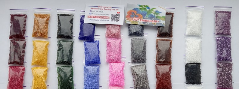 May include: A collection of small, colorful beads in clear plastic bags, arranged in rows. The beads come in various colors, including red, yellow, blue, pink, and white. A business card with the text "Easy Embroidery" is also visible.