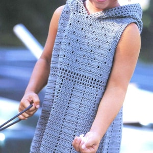 May include: A young girl wearing a light blue crocheted sleeveless dress with a hood. She is smiling and has a pink headband in her hair.