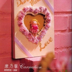 May include: A handmade card with a pink carnation flower heart frame, a small doll holding a heart, and the words "Dear Mom" and "Love" in gold lettering.