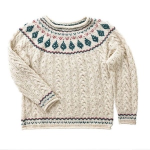 May include: A cream-colored knitted sweater with a dark green, red, and white patterned yoke. The sweater has a cable knit design and a ribbed hem and cuffs.