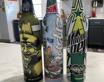 3 latas de refresco de aluminio Mountain Dew con gráficos pintados nuevos sellados