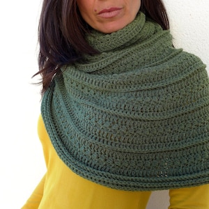 Może przedstawiać: Zielony komin lub szalik wykonany na szydełku z fakturowanym wzorem. Komin jest złożony i noszony wokół szyi.