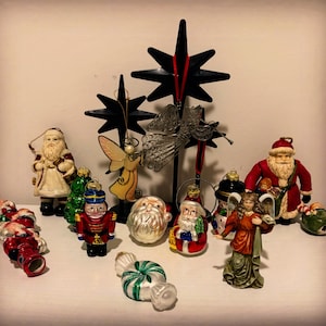 May include: A collection of Christmas ornaments, including Santa Claus figures, angels, a nutcracker, and a star-shaped tree topper. The ornaments are in various colors, including red, green, gold, and white. The scene evokes a festive holiday atmosphere.