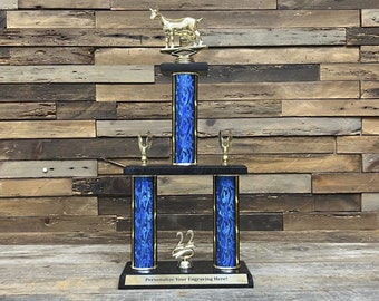 May include: A three-tiered trophy with a gold goat figurine on top. The trophy has blue columns with a flame design, gold accents, and small gold cup figurines. The base is black with the text "Personalize Your Engraving Here!"