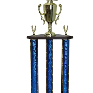 May include: A gold trophy with a football player figure on top. The trophy has a gold cup, a dark brown base, and three blue columns with a flame design. The base has the text "PERSONALIZED MESSAGE HERE".