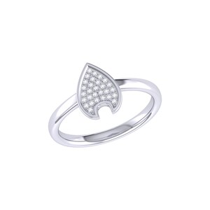Op de afbeelding: Een zilverkleurige ring met een puntig, schildvormig middendeel. De voorzijde van het schild is ingelegd met een cluster van kleine, heldere, fonkelende steentjes in een rasterpatroon, op een gladde, gepolijste metalen ring.