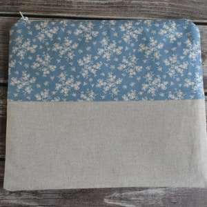 Puede incluir: Una bolsa con cremallera azul y beige con un patrón floral. La bolsa está hecha de tela y tiene un cierre de cremallera.