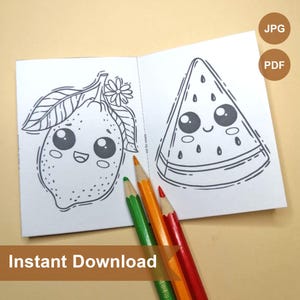 May include: A black and white coloring book with two pages showing a lemon and a watermelon with cute faces. The book is open and there are three colored pencils on top of it.