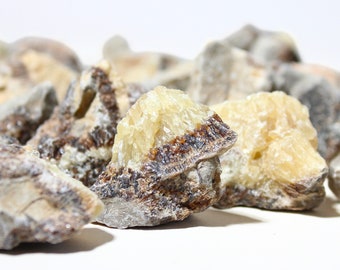 Puede incluir: Primer plano de un grupo de especímenes minerales marrones y blancos. El mineral tiene una superficie rugosa y texturizada y una estructura cristalina.