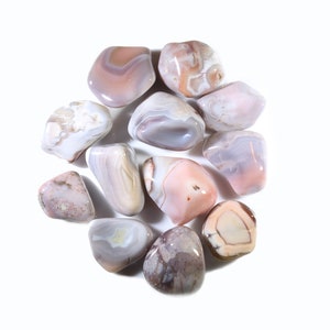 May include: A collection of ten tumbled agate stones in shades of pink, white, and gray. The stones are smooth and polished, with intricate patterns of banding and swirls.