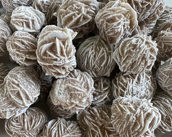 May include: A pile of brown and white desert rose crystals. The crystals are clustered together and have a rough, textured surface.