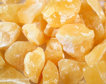 May include: A close-up of a group of orange calcite crystals. The crystals are rough and have a natural, unpolished look.