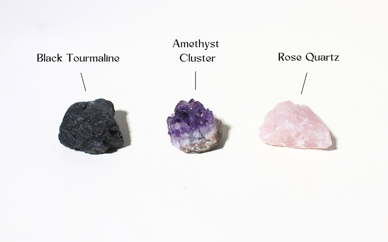 May include: Three different types of crystals: a black tourmaline, an amethyst cluster, and a rose quartz.