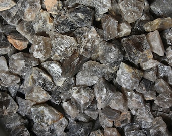 May include: A close-up view of a pile of smoky quartz crystals. The crystals are various sizes and shapes, with a translucent, smoky gray color.