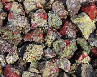 May include: A close-up of a pile of green and red jasper stones. The stones are rough and have a natural, unpolished finish.
