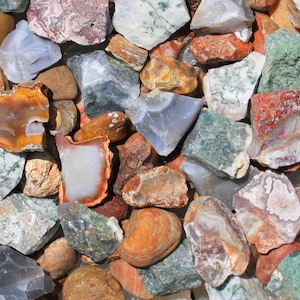 May include: A collection of colorful agate stones in various shapes and sizes. The stones have a variety of patterns and colors, including brown, white, green, and red.