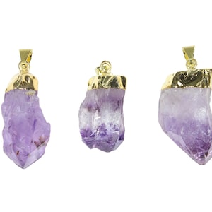 K&ouml;nnte beinhalten: Drei Amethyst-Kristall-Anh&auml;nger mit vergoldeten Oberteilen. Die Kristalle sind roh und haben einen violetten Farbton.