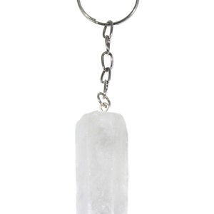 May include: A clear quartz crystal keychain with a silver-colored chain and key ring. The crystal is a rectangular shape with a pointed end. The keychain is against a white background.