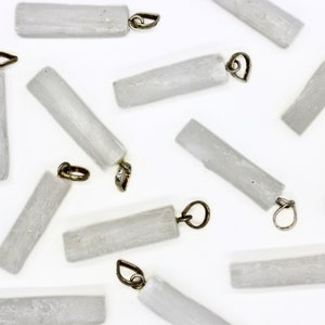 May include: A collection of white selenite crystal pendants with silver-toned metal loops. The crystals are smooth and polished, with a natural, slightly cloudy appearance.