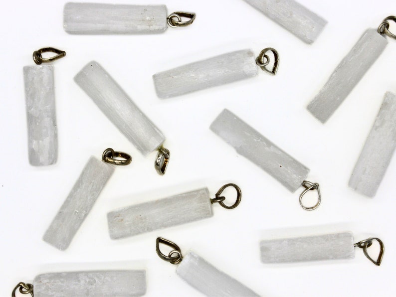 May include: A collection of white selenite crystal pendants with silver-toned metal loops. The crystals are smooth and polished, with a natural, slightly cloudy appearance.
