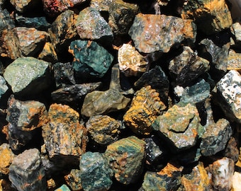 May include: A close-up of a pile of green and yellow jasper stones. The stones are rough and have a natural, unpolished finish.