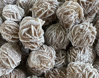 May include: A close-up of a group of rose quartz crystals. The crystals are a light brown color and have a rough, textured surface. They are arranged in a random pattern.