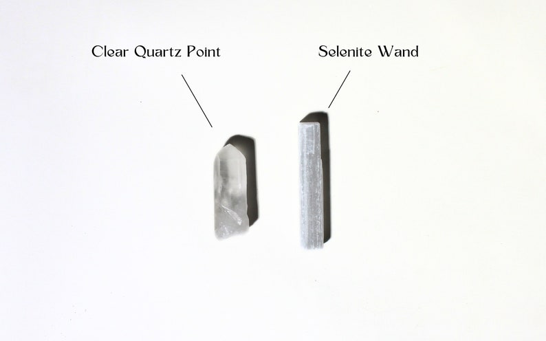 May include: A clear quartz point and a selenite wand, both white crystals, are displayed on a white surface. The text "Clear Quartz Point" is above the quartz point and the text "Selenite Wand" is above the wand.