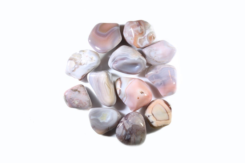 May include: A collection of ten tumbled agate stones in shades of pink, white, and gray. The stones are smooth and polished, with intricate patterns of banding and swirls.