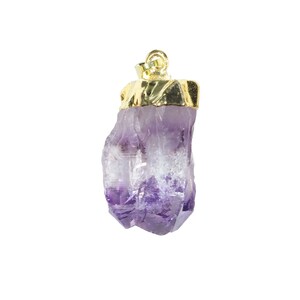 K&ouml;nnte beinhalten: Ein Anh&auml;nger aus violettem Amethystkristall mit einer goldenen Fassung. Der Kristall hat eine nat&uuml;rliche, rohe Form mit einer spitzen Spitze.
