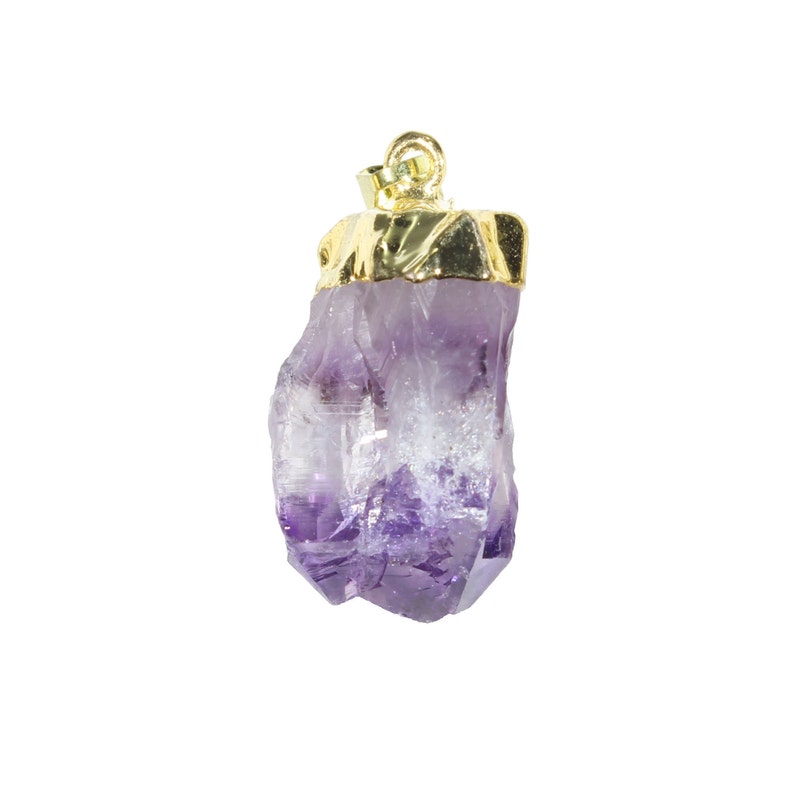 K&ouml;nnte beinhalten: Ein Anh&auml;nger aus violettem Amethystkristall mit einer goldenen Fassung. Der Kristall hat eine nat&uuml;rliche, rohe Form mit einer spitzen Spitze.