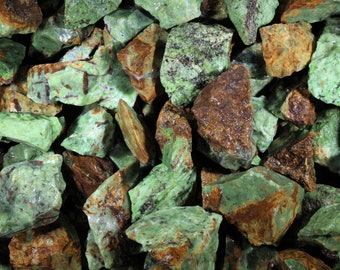 May include: A close-up of a collection of green and brown rough gemstones. The stones are irregularly shaped and have a natural, unpolished finish.