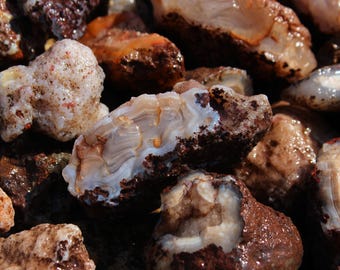 May include: Close-up of a collection of polished agate stones. The stones display a variety of colors, including white, brown, and orange, with intricate banding patterns. The surface of the stones is smooth and reflective, with a wet appearance.