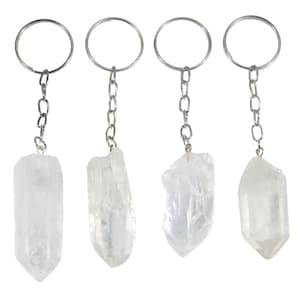 May include: Four clear quartz crystal keychains. Each keychain features a raw, natural quartz crystal pendant attached to a silver-tone chain and keyring. The crystals vary slightly in shape and size, showcasing their unique, natural formations.