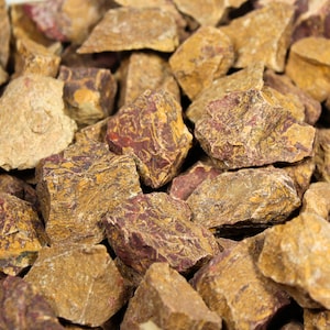 May include: A close-up of a pile of red and brown jasper stones. The stones have a swirling pattern of red and brown.