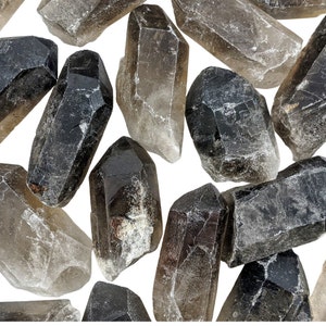 May include: A collection of smoky quartz crystal points in various sizes and shades of brown and gray. The crystals are faceted and have a natural, raw appearance, with a range of translucency.