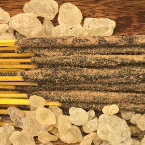 May include: A close-up of a bundle of incense sticks with a brown and black color. The incense sticks are surrounded by clear, translucent crystals.