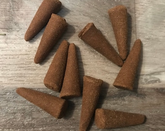 Könnte beinhalten: Zehn braune Räucherkegel, die in Sternform auf einer Holzoberfläche angeordnet sind.