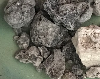 Può includere: Primo piano di un mucchio di cristalli di sale di roccia grigio scuro e bianco. I cristalli di sale hanno una forma irregolare e una consistenza ruvida.
