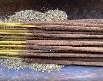 Puede incluir: Un paquete de varillas de incienso marrones con un núcleo de madera amarillo, dispuestas sobre una cama de virutas de madera secas.