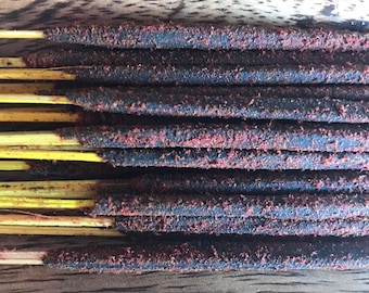 Könnte beinhalten: Ein Bündel dunkelbrauner Räucherstäbchen mit einer rotbraunen Pulverbeschichtung. Die Stäbchen sind in einer Reihe auf einer Holzoberfläche angeordnet.