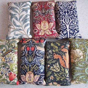 Peut inclure: Plusieurs coussins rectangulaires décoratifs avec des motifs floraux et botaniques variés. Les coussins présentent des couleurs telles que le bleu, le rouge, le vert et le crème, avec des motifs de feuilles, de fleurs et de baies.