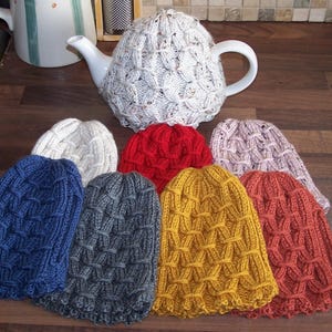 May include: A collection of seven knitted hats in various colours, including blue, red, grey, white, and brown. The hats are all made with a similar stitch pattern and have a textured look.