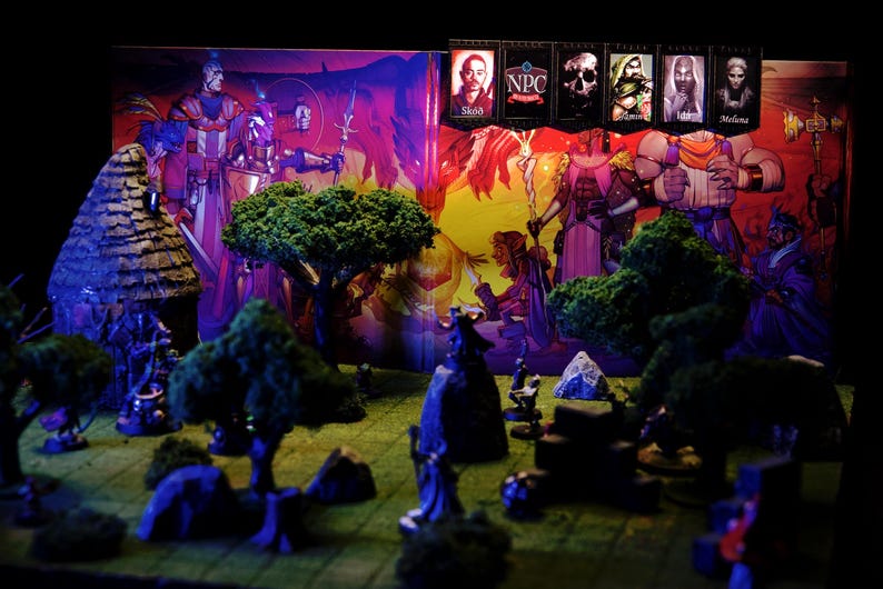 Puede incluir: Una escena de juego de rol de mesa con figuras en miniatura, &aacute;rboles y un tel&oacute;n de fondo con personajes de fantas&iacute;a. El tel&oacute;n de fondo incluye pancartas con retratos de personajes y el texto "NPC". La escena est&aacute; iluminada con luz p&uacute;rpura y amarilla.