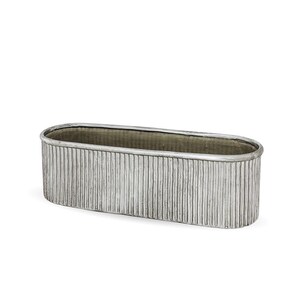 Op de afbeelding: Een ovaalvormige plantenbak met een metallic zilveren afwerking en een verticaal geribbelde textuur langs de buitenwanden. De container heeft een gladde, afgeronde rand en een diepe, open binnenkant met een consistente industriële uitstraling.